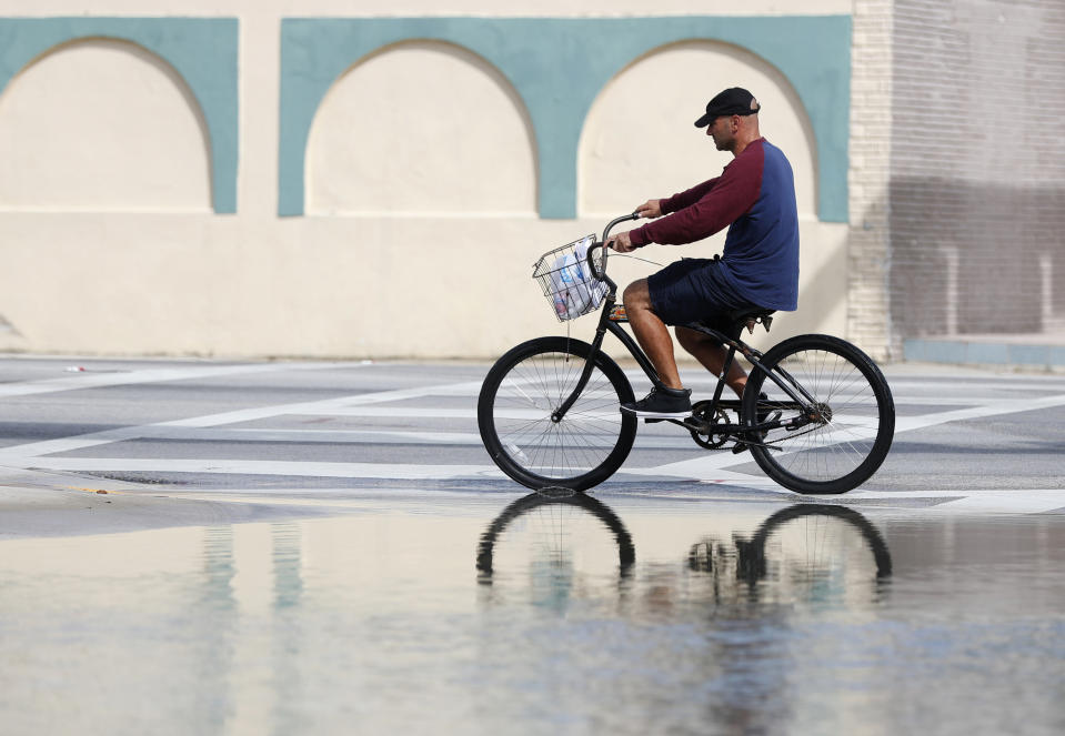 FILE - In this Oct. 9, 2018, file photo, a cyclist rides past an area flooded during a King Tide, an especially high tide, in Miami. Federal scientists, according to a report released Wednesday, July 10, 2019, predict 40 places in the U.S. will experience higher than normal rates of so-called sunny day flooding this year due to rising sea levels and an abnormal El Nino weather system. (AP Photo/Wilfredo Lee, FIle)