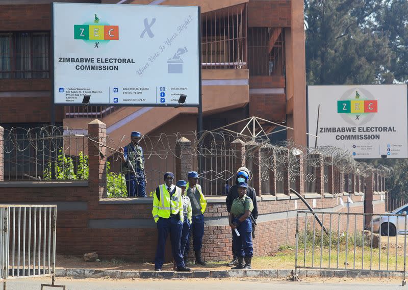 Members of the police stand guard near barricades at the Zimbabwe Election Commission (ZEC) offices as vote counting progresses in Harare