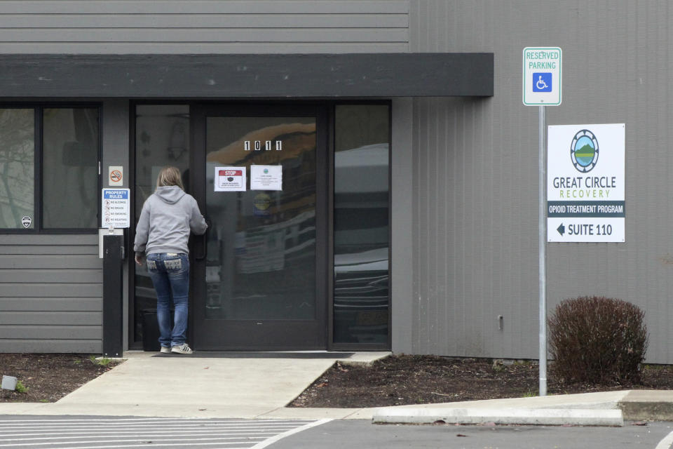 A woman enters the Great Circle drug treatment center in Salem, Oregon, on March 8, 2022. The center gets funding from Oregon's pioneering drug decriminalization law and illustrates an aspect of the new system, one year after it took effect. (AP Photo/Andrew Selsky)