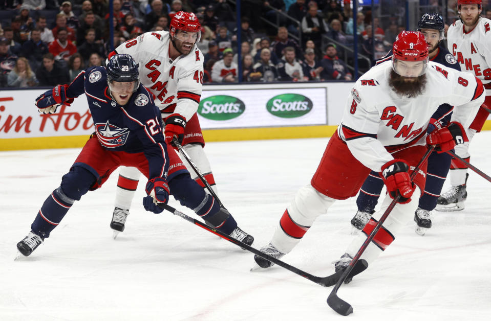 Carolina Hurricanes defenseman Brent Burns, right, controls the puck in front of Columbus Blue Jackets forward Patrik Laine, left, and Hurricanes forward Jordan Martinook during the second period of an NHL hockey game in Columbus, Ohio, Thursday, Jan. 12, 2023. (AP Photo/Paul Vernon)