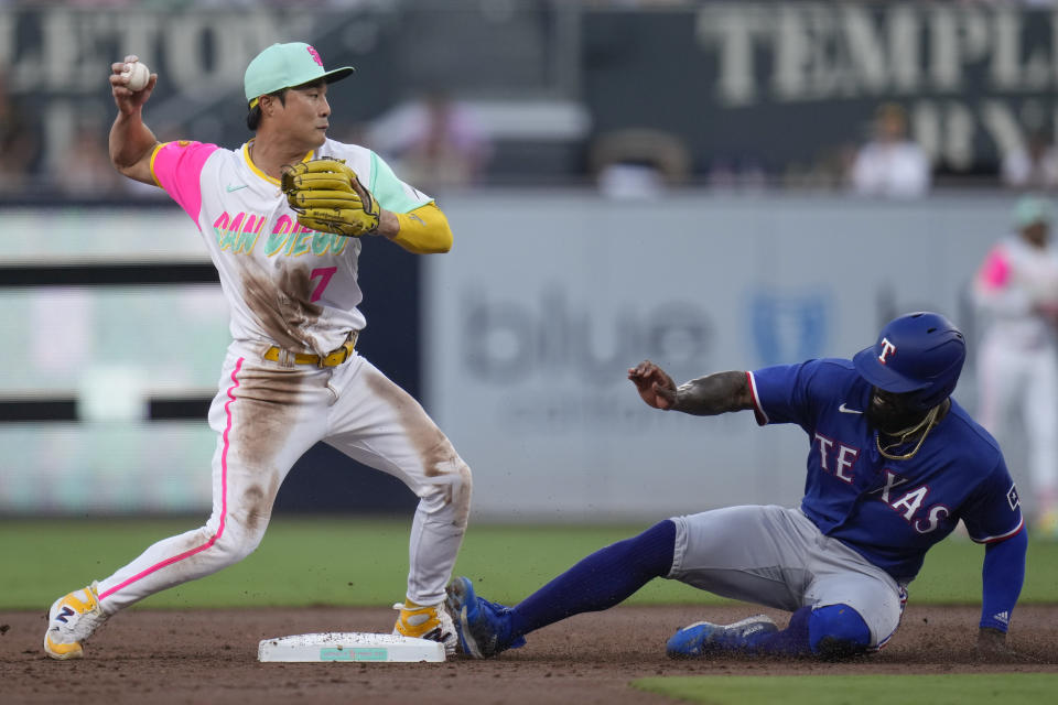 San Diego Padres second baseman Ha-Seong Kim, left, throws to first too late for the double play as Texas Rangers' Adolis Garcia slides in late to second base during the second inning of a baseball game Friday, July 28, 2023, in San Diego. Texas Rangers' Josh Jung was safe at first on the force out. (AP Photo/Gregory Bull)
