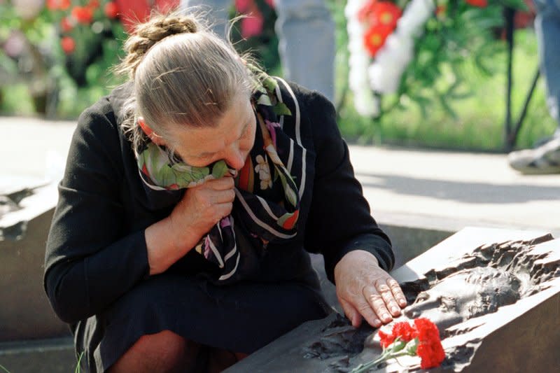 Valentina Lopatyuk cries near the bas-relief portrait of her son Viktor on his grave at a cemetery in Moscow on April 26, 2000, on the anniversary of the 1986 Chernobyl disaster. File Photo by Maxim Marmur/UPI