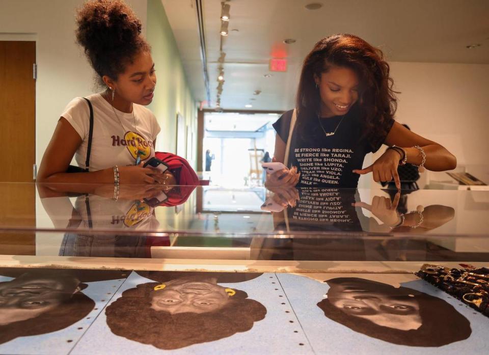 Las estudiantes de FIU Loralei González (izquierda) y Nadia De La Mora observan la obra de técnica mixta de Chire Regans 'We Remember, We Remain'. Carl Juste cjuste@miamiherald.com