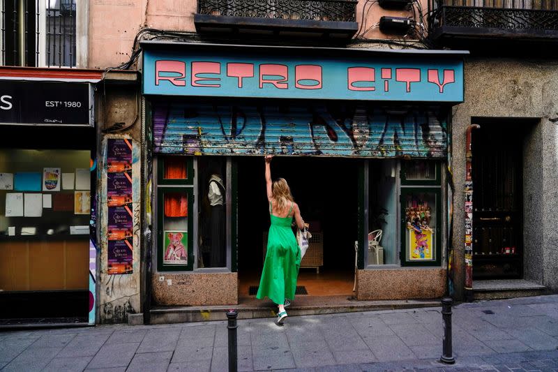FILE PHOTO: A woman opens a shop at a commercial district in Madrid
