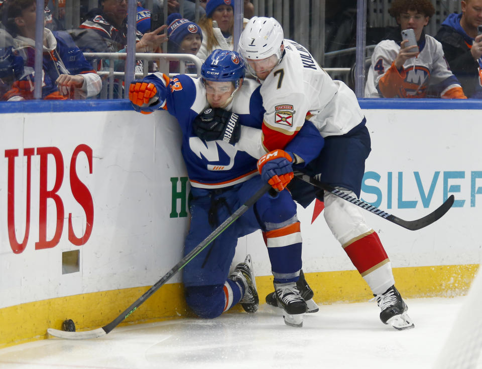 New York Islanders center Mathew Barzal (13) and Florida Panthers defenseman Dmitry Kulikov (7) battle along the boards during the second period of an NHL hockey game, Saturday, Jan. 27, 2024, in Elmont, N.Y. (AP Photo/John Munson)