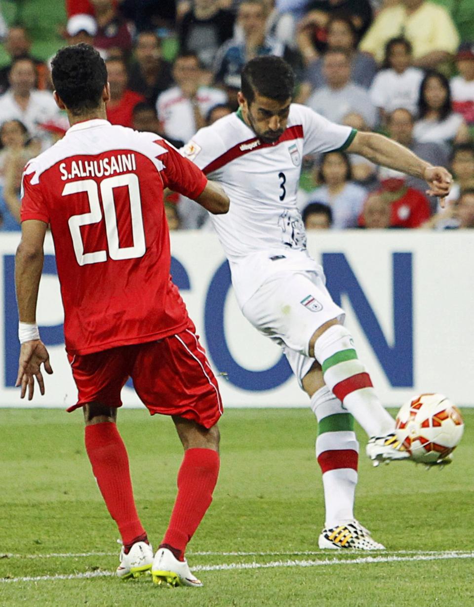Iran's Ehsan Hajisafi shoots to score a goal next to Bahrain's Sami Al-Husaini during their Asian Cup Group C soccer match at the Rectangular stadium in Melbourne