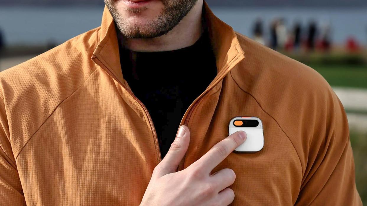  A person tapping on the Humane AI Pin worn on their jacket. 