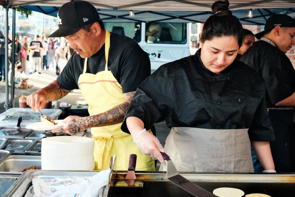 Roy Choi prepares a taco while a member of his team flips tortillas