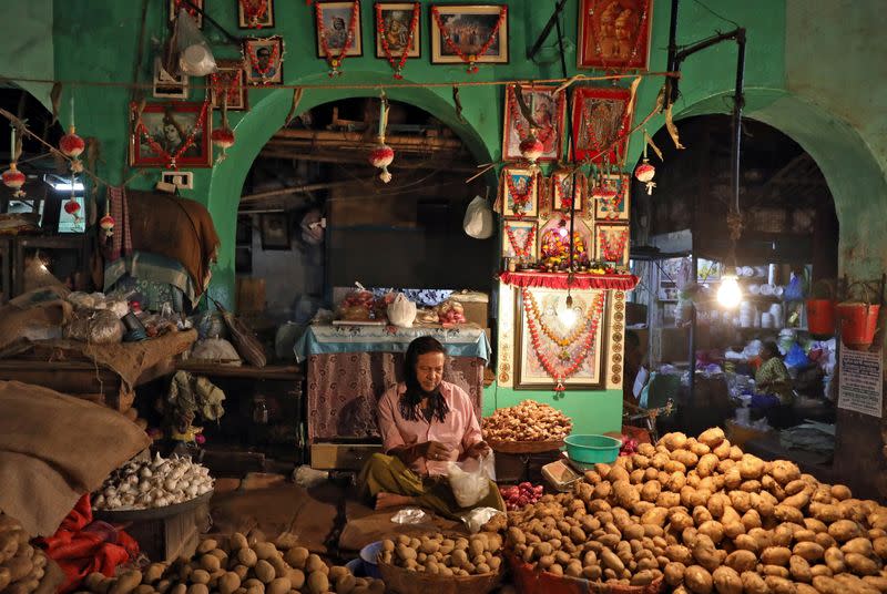 A vendor waits for customers at his shop inside a vegetable market in Kolkata