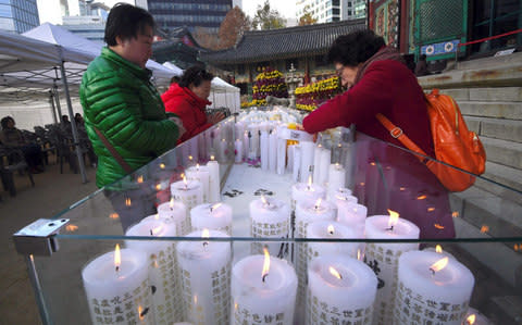 Women place candles for the success of their relatives sitting the annual College Scholastic Ability Test, at the Jogye Buddhist temple in Seoul on November 23, 2017 - Credit:  AFP