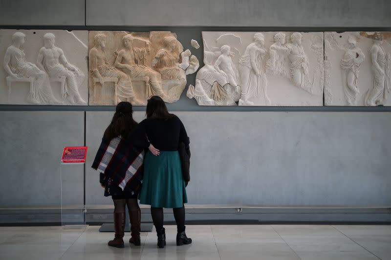 Visitors look at original sculptures and plaster cast copies of the frieze of the Parthenon temple at the Parthenon Gallery of the Acropolis Museum, in Athens