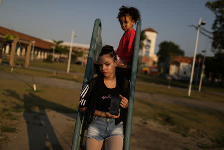 Eduarda Lopes, 12, poses for a photograph as she holds up a picture of her mother on her phone in the Manguinhos slum in Rio de Janeiro, Brazil, September 13, 2018. Lopes's mother, Valdilene da Silva, was killed in crossfire as they walked together. REUTERS/Pilar Olivares