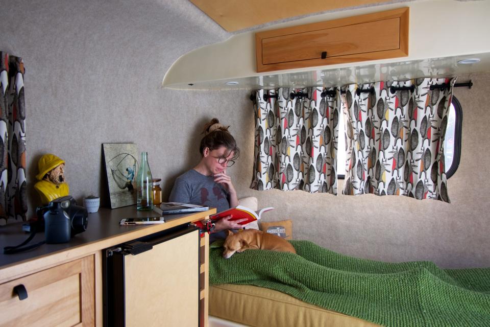 A woman in a bed in a travel trailer.