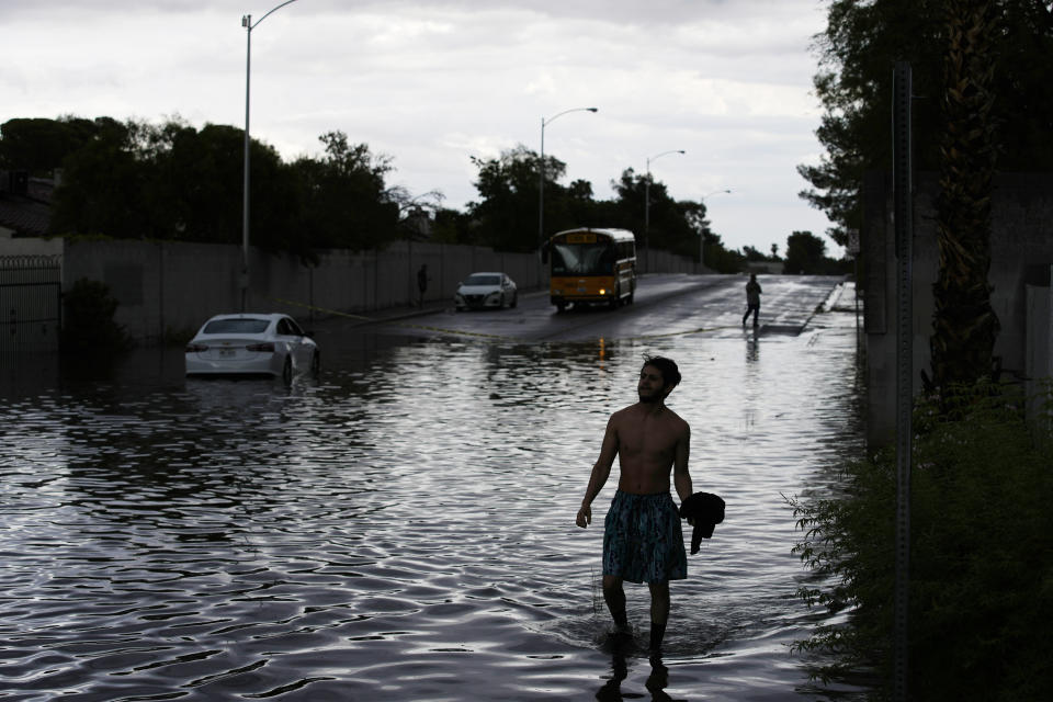 A person walks through floodwaters near a stranded car, Friday, Sept. 1, 2023, in Las Vegas. (AP Photo/John Locher)