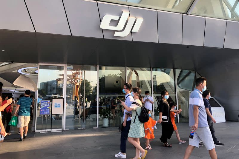 FILE PHOTO: People wearing face masks following the coronavirus disease (COVID-19) outbreak walk past DJI's flagship store in Shenzhen