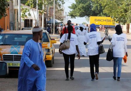 A man turns his head as election observers walk on a street during the presidential election in Banjul, Gambia, December 1, 2016. REUTERS/Thierry Gouegnon