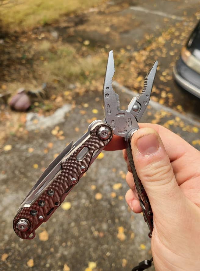 Person's hand holding a multi-tool with pliers extended