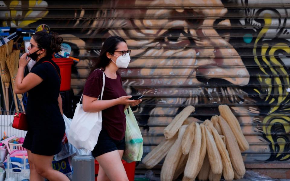 Shoppers wearing protective masks amid the COVID-19 pandemic walk past stalls at the Mahane Yehuda market in Jerusalem  - AFP