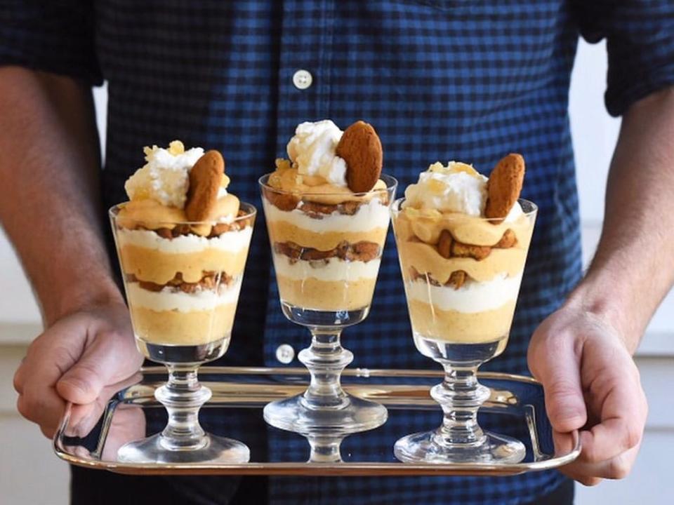 Man holding silver tray of pumpkin parfaits topped with whipped cream