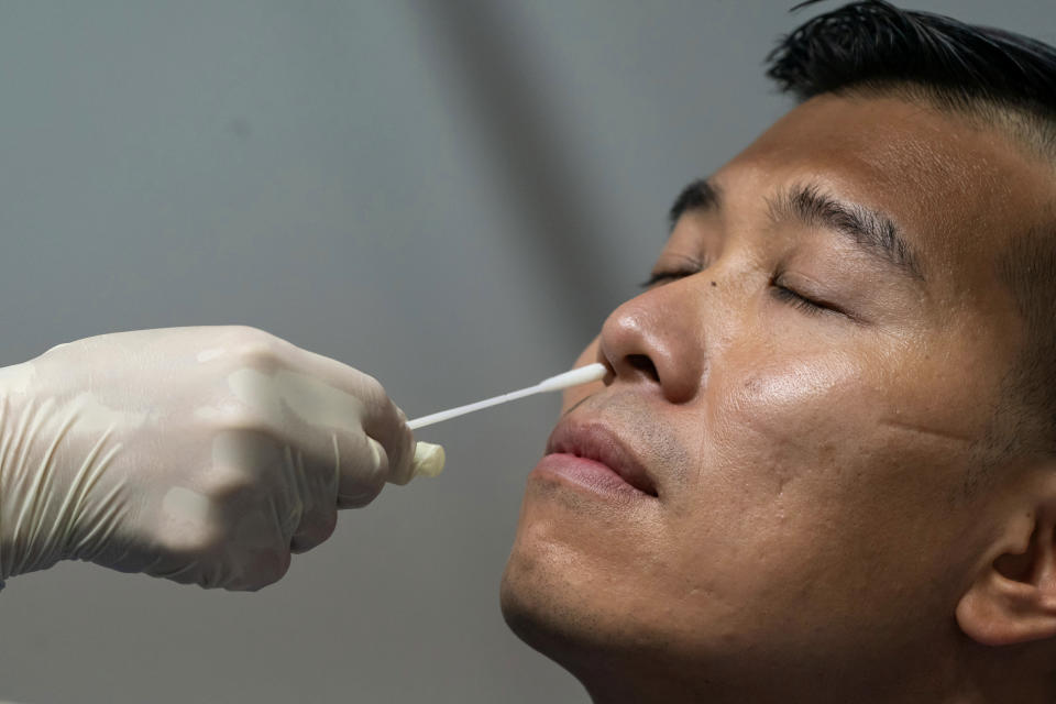 Nasal swab sample is collected from a man by a medical worker at a makeshift testing site in the Queen Elizabeth Stadium in Hong Kong Tuesday, Sept. 1, 2020. Hong Kong began a voluntary mass-testing program for coronavirus Tuesday as part of a strategy to break the chain of transmission in the city's third outbreak of the disease. (Anthony Kwan /Pool Photo via AP)