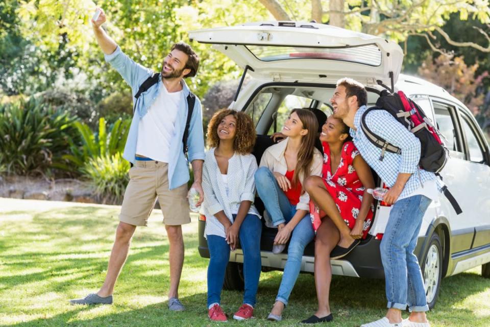 Group of happy friends taking a selfie from trunk of car