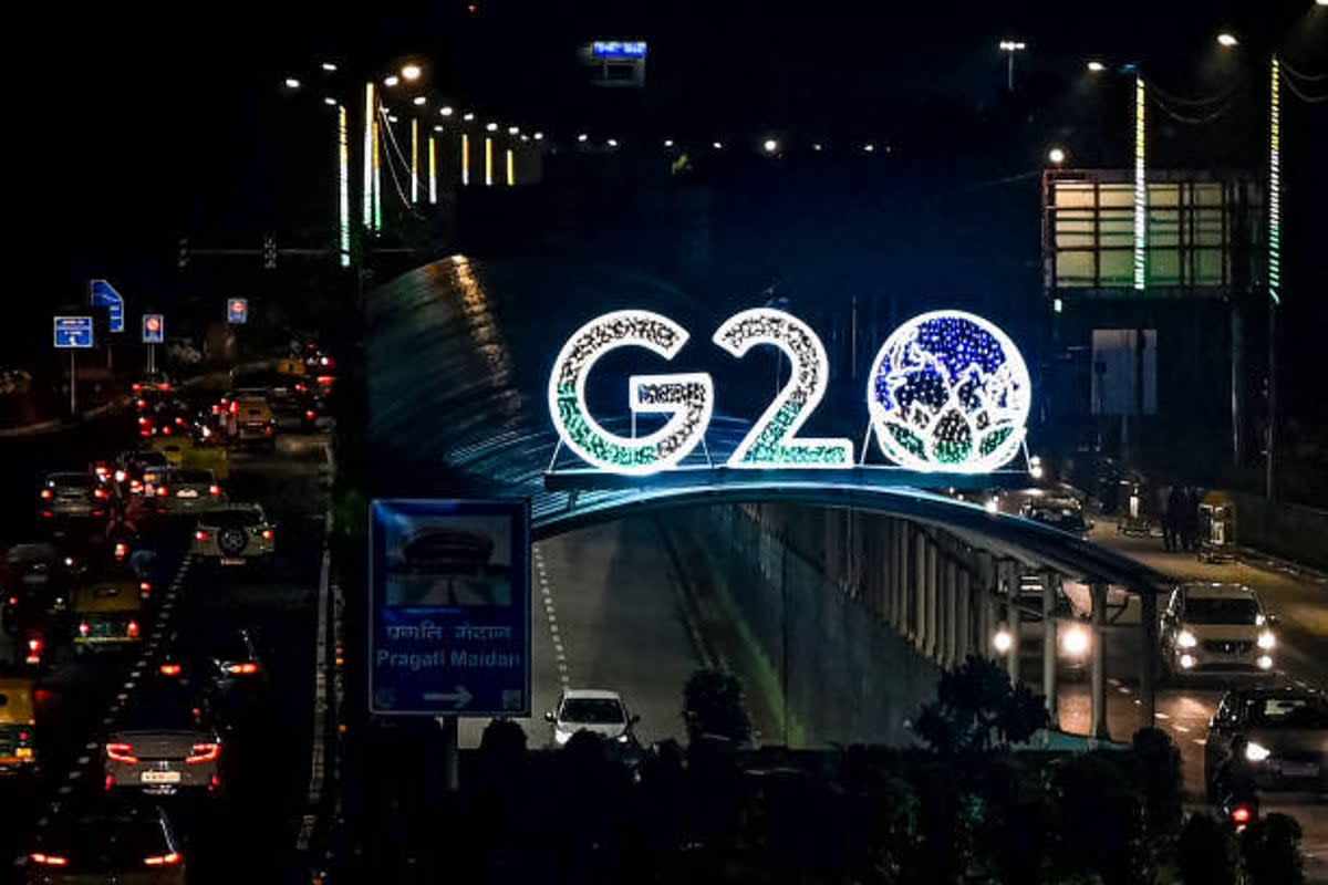 Vehicles drive past the logo of India’s G20 summit, along a road in New Delhi on 10 August 2023 (AFP via Getty Images)