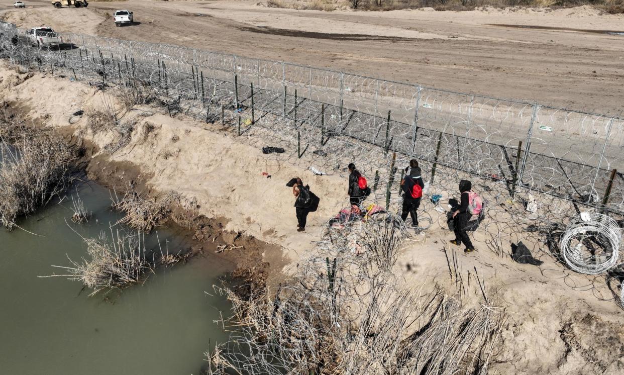 <span>An aerial view of the area as migrants walking along razor wire after crossing the Rio Grande into the US on 28 January 2024 in Eagle Pass, Texas. </span><span>Photograph: Anadolu/Getty Images</span>