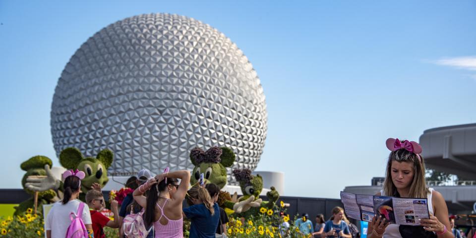 A tourist looks at a park map during the Flower and Garden Festival at Epcot at Walt Disney World in Orange County, Florida on May 30, 2022.