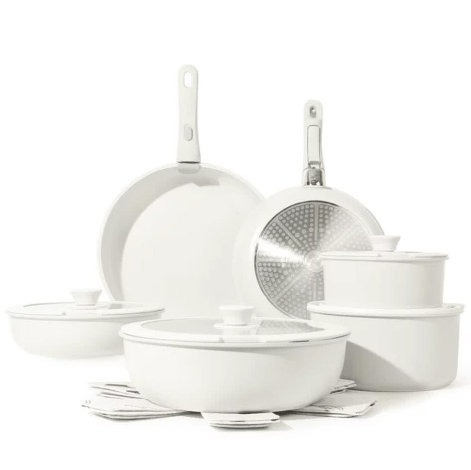 Set of white kitchenware with pans, pots, and lids against a white background