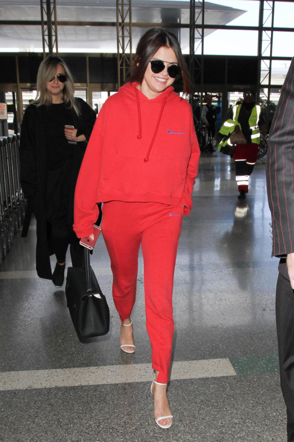 <p>Gomez headed to her flight at LAX wearing a red sweat suit by cult-favorite French brand Vetements (the logo rips off that of classic athletic brand Champion) with white heeled sandals. This is how you’d dress at the airport too, if you didn’t have to schlep your own wheelie suitcase. <i>Photo: Getty Images</i></p>