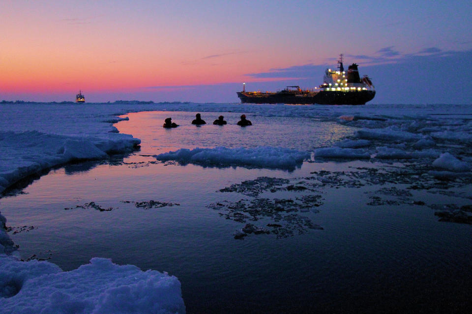 Crewmembers from the Coast Guard Cutter Bristol Bay take a dip in Lake Erie at sunset with the Canadian Coast Guard Ship Griffon and the motor vessel Algoma Hansa in the background, March 8, 2015. 