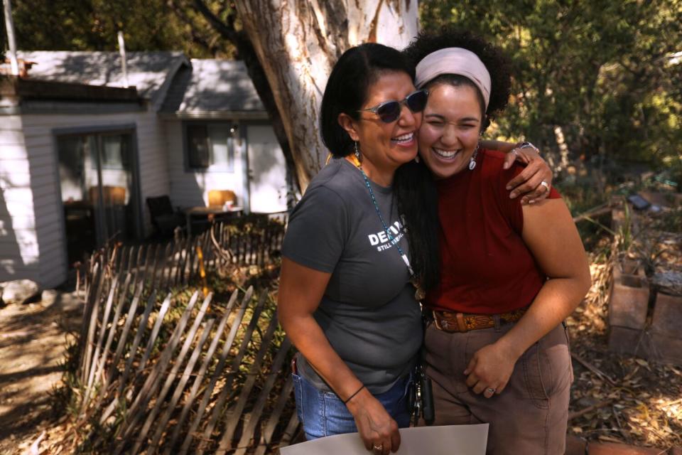 Two women smile with their arms around each other