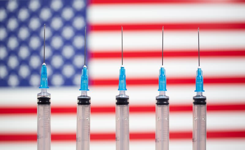 Syringes are seen in front of a displayed U.S. flag in this illustration