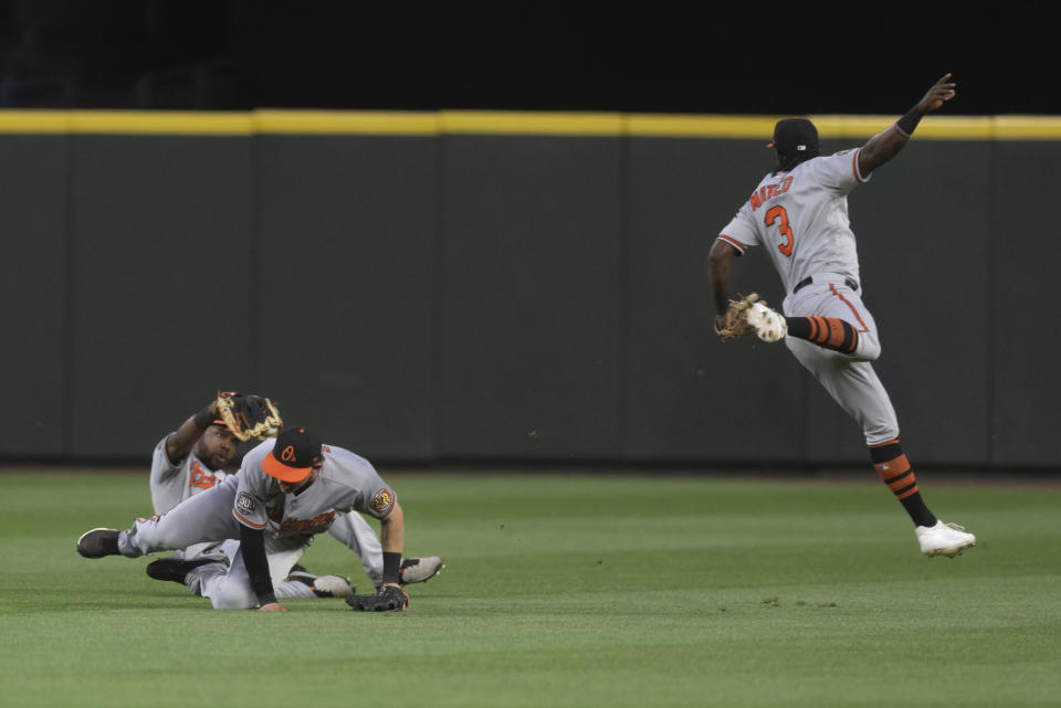 Baltimore Orioles centerfielder Cedric Mullins, left, makes a catch on a ball hit by Seattle Mariners' Taylor Trammell after near collisions with Baltimore Orioles rightfielder Austin Hays, and shortstop Jorge Mateo, right, during the sixth inning of a baseball game, Monday, June 27, 2022, in Seattle. (AP Photo/Stephen Brashear)