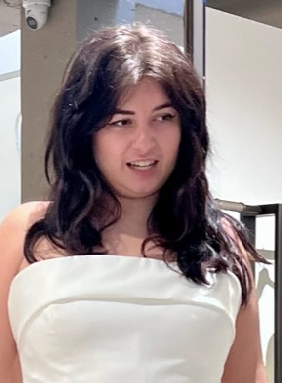 Woman in a white strapless outfit smiling slightly, indoors