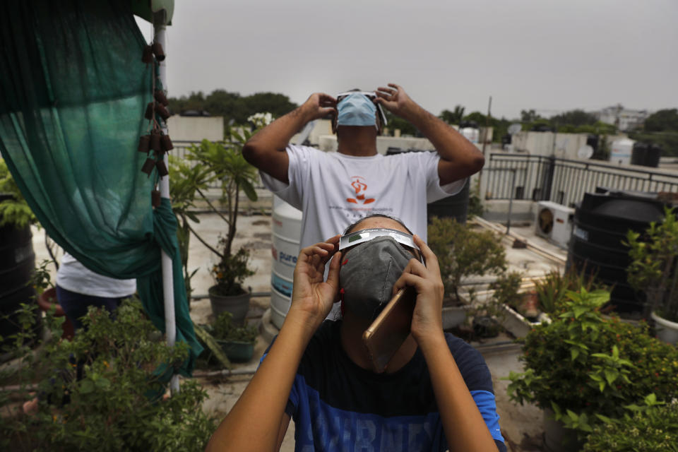 A father and his daughter watch solar eclipse from the roof of a house in New Delhi, India, Sunday, June 21, 2020. (AP Photo/Manish Swarup)