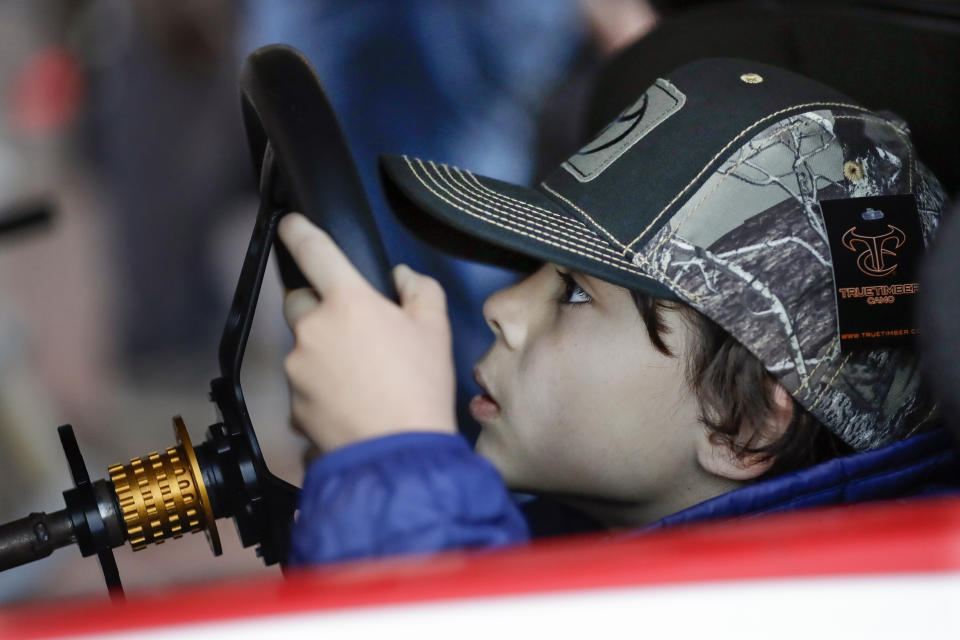 Noah Michel, 8, of Los Angeles, peeks through the steering wheel as he drives a racing simulator Wednesday, Dec. 4, 2019, during NASCAR Champion's Week in Nashville, Tenn. (AP Photo/Mark Humphrey)