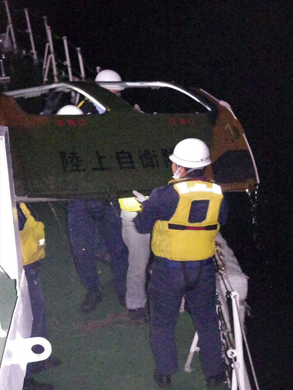 In this photo provided by the 11th Regional Japan Coast Guard Headquarters, coast guard members retrieve a door from the sea, off Miyako Island, Okinawa Prefecture, southern Japan, Friday, April 7, 2023. The words on the door reads Ground Self Defense Force. Search and rescue operation continued Friday and officials said they found a door and other fragments believed to be of a Japanese army helicopter presumed to have crashed into the sea near southern islands with 10 crew members on board. (11th Regional Japan Coast Guard Headquarters via AP)