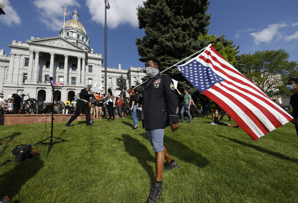 Aubrey Rose, who earned the rank of staff sergeant while serving four tours of duty in the U.S. Army, carries a flag during a protest outside the State Capitol over the death of George Floyd, a handcuffed black man in police custody in Minneapolis, Thursday, May 28, 2020, in Denver. Close to 1,000 protesters walked from the Capitol down the 16th Street pedestrian mall during the protest. (AP Photo/David Zalubowski)