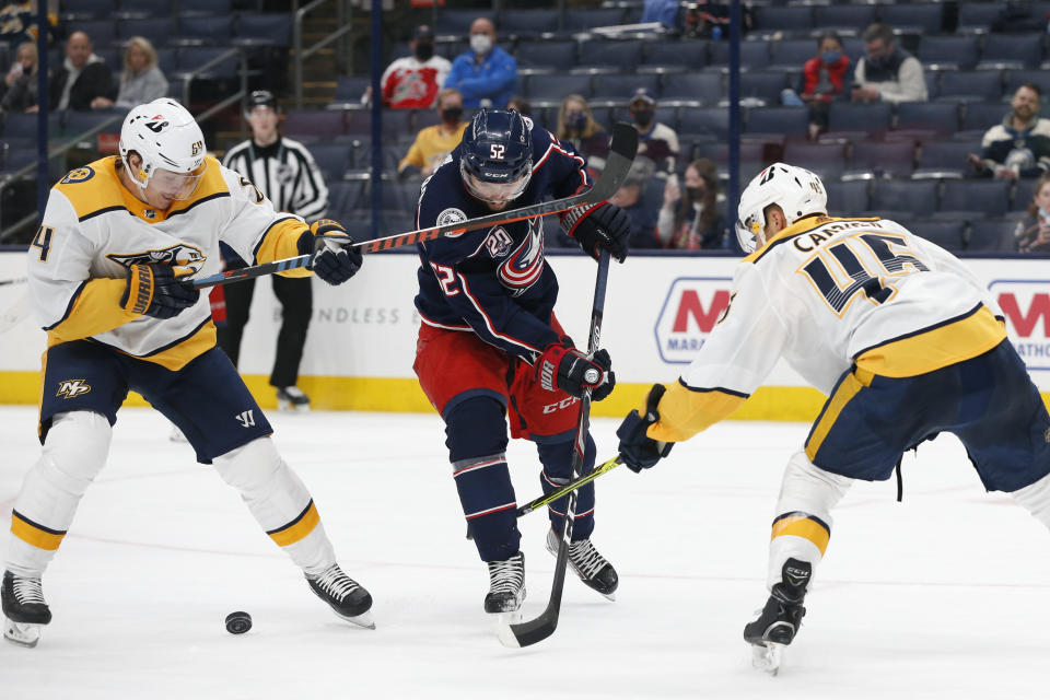 Columbus Blue Jackets' Emil Bemstrom, center, tries to shoot the puck between Nashville Predators' Mikael Granlund, left, and Alexandre Carrier during the second period of an NHL hockey game Wednesday, May 5, 2021, in Columbus, Ohio. (AP Photo/Jay LaPrete)