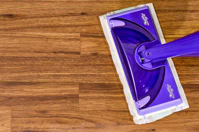 overhead shot of a swiffer cleaning a bare hardwood floor.