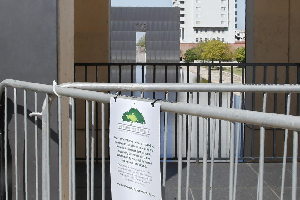 The 9:02 gate at the Oklahoma City National Memorial and Museum is pictured behind a sign announcing the closure of the site, Wednesday, April 15, 2020, in Oklahoma City. Due to COVID-19 concerns, the site scaled back its plans for a 25th anniversary remembrance and will instead offer a recorded, one-hour television program that includes the reading of the names of the 168 people killed in the bombing followed by 168 seconds of silence, instead of the annual open-to-the-public ceremony. (AP Photo/Sue Ogrocki)