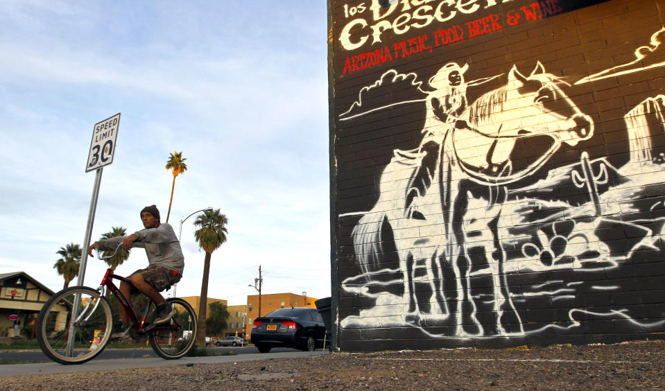 A cyclist pedals on Roosevelt Street along the Roosevelt Row neighborhood Tuesday, Nov. 27, 2012, in Phoenix. The neighborhood is home to First Friday Art Walk, a Phoenix tradition since 1994, promoting local artists and shops.(AP Photo/Ross D. Franklin)