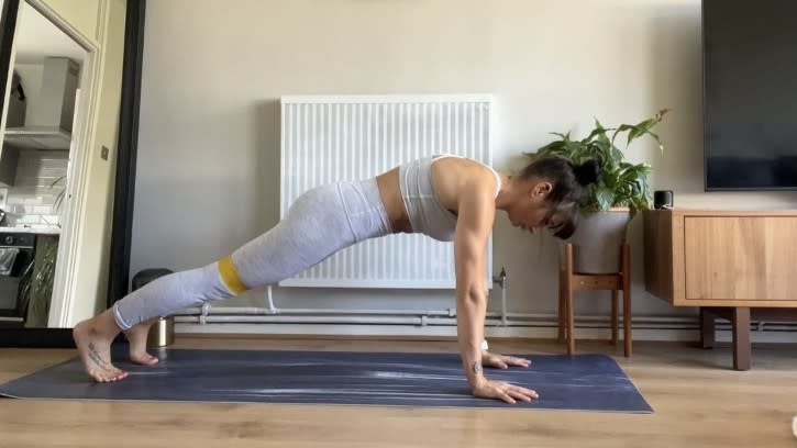 Writer Sam performing a high plank with band above knees at home during workout