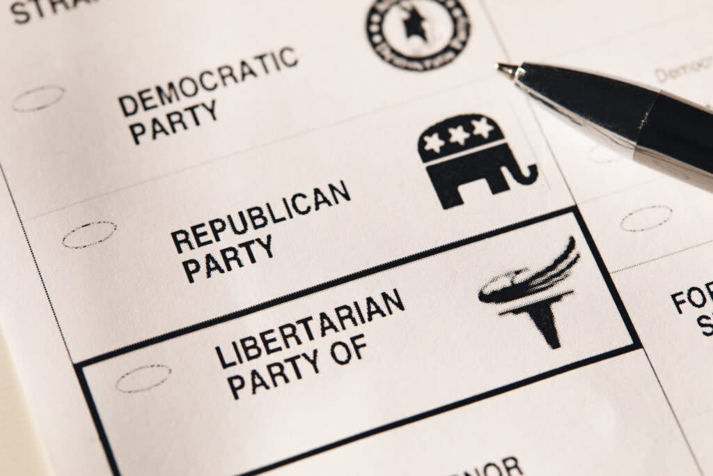 A pen hovering over a black and white ballot showing the Democratic Party, the Republican Party and the Libertarian Party.