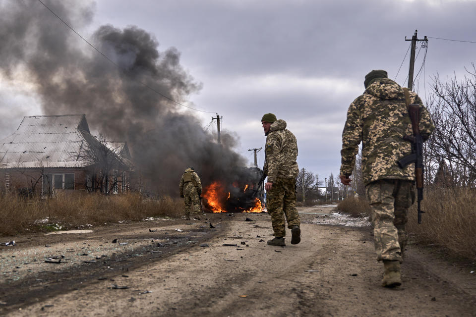 In this photo provided by the Ukrainian 10th Mountain Assault Brigade "Edelweiss", Ukrainian soldiers pass by a volunteer bus burning after a Russian drone hit it near Bakhmut, Donetsk region, Ukraine, Thursday, Nov. 23, 2023. (Shandyba Mykyta, Ukrainian 10th Mountain Assault Brigade "Edelweiss" via AP)