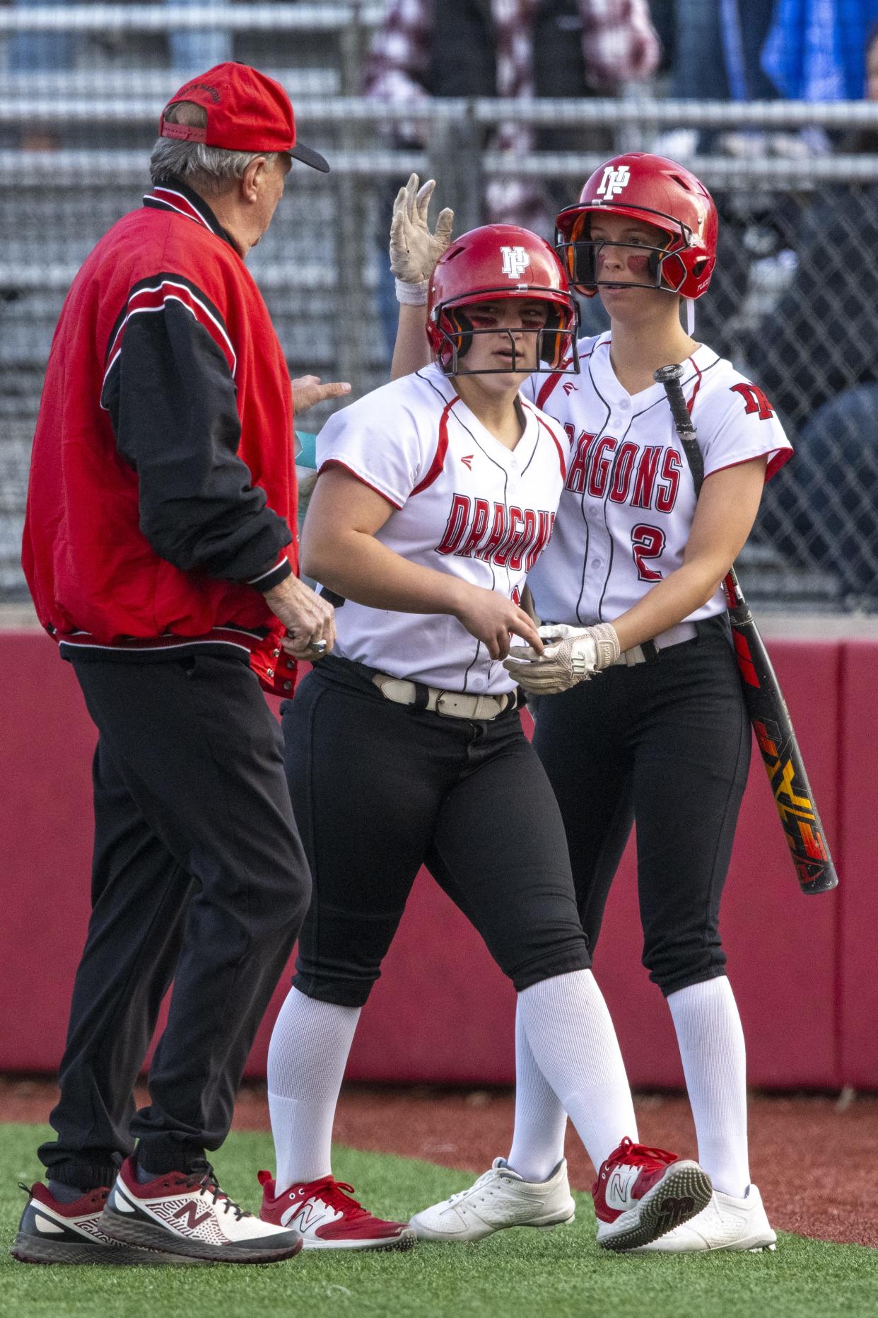 New Palestine High School freshman Payton Dye (12), center, reacts after scoring during an IHSAA softball game against Zionsville High School, Friday, April 19, 2024, at New Palestine High School. New Palestine won, 6-1.