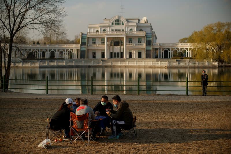 People wearing protective masks play cards in a park on a sunny day in Beijing as the country is hit by an outbreak of the novel coronavirus disease (COVID-19)