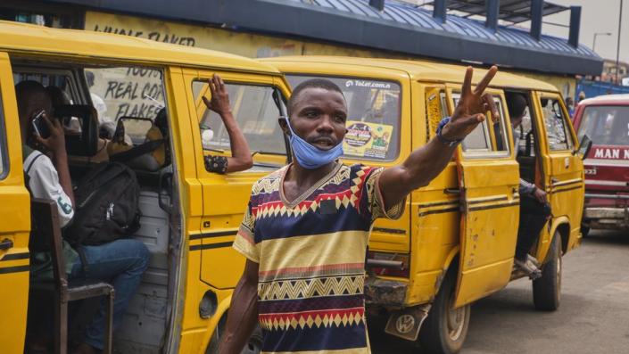 A driver stands in front of a Lagos danfo