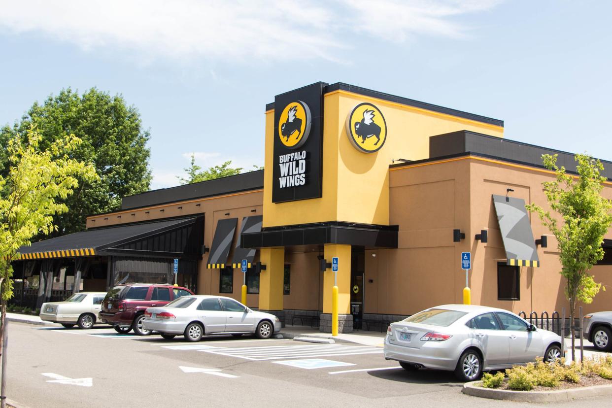 Exterior of a Buffalo Wild Wings restaurant in Eugene, Oregon with front area and surrounding parking lot with trees on a sunny summer day